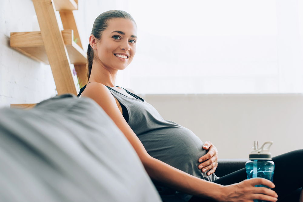 A young pregnant woman smiles as she considers getting LASIK eye surgery.